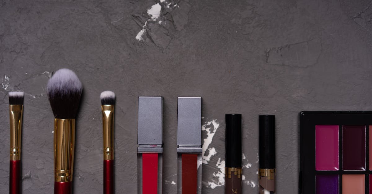High-quality flat lay of various makeup brushes and cosmetics on textured background.